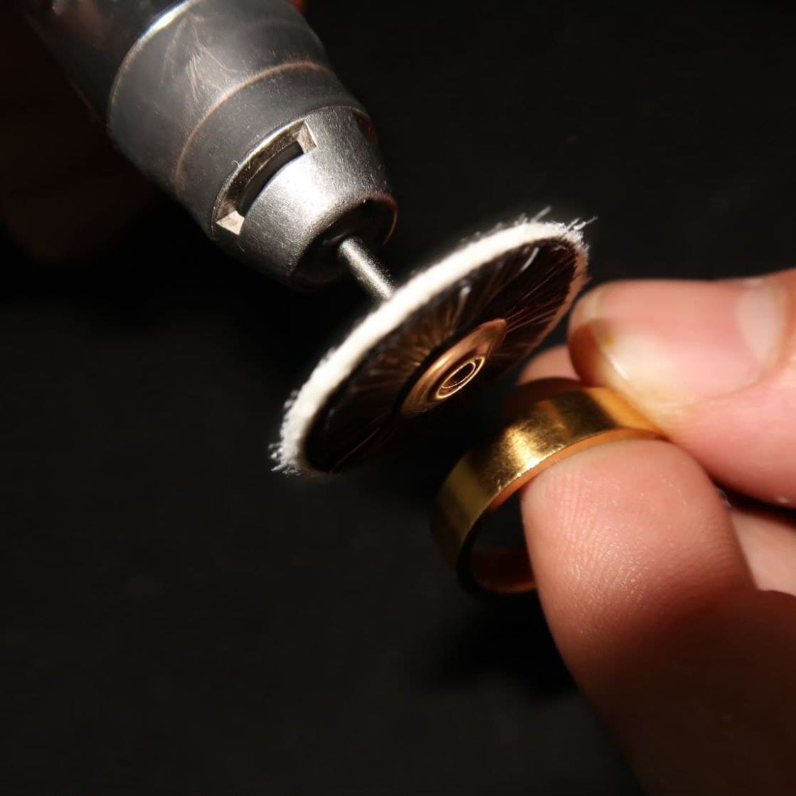 Ein Goldring wird an der Werkbank mit einem Polieraufsatz bearbeitet